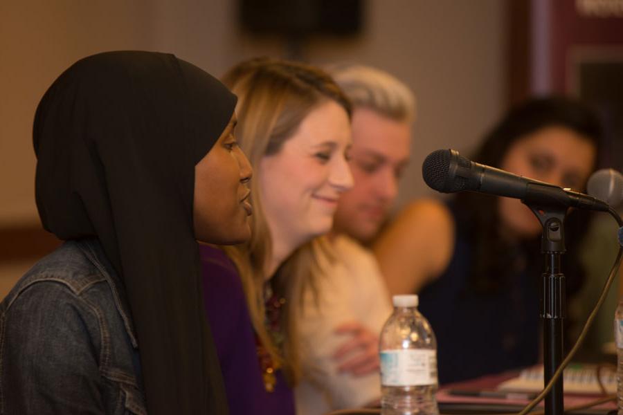 Four panelists discussing human rights and social justice. The person speaking is wearing a hijab.